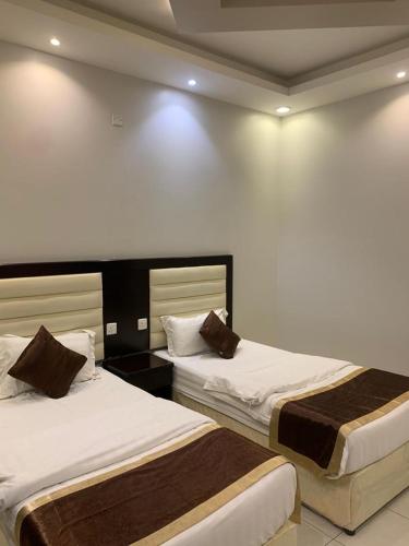 2 letti in una camera d'albergo con pareti bianche di ركن الهدوء a Muhayil
