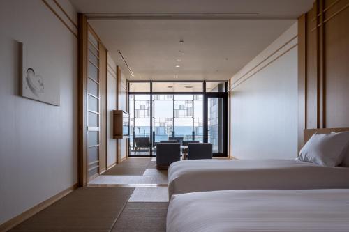 a hotel room with a bed and a table and chairs at Pearl Star Hotel ATAMI in Atami