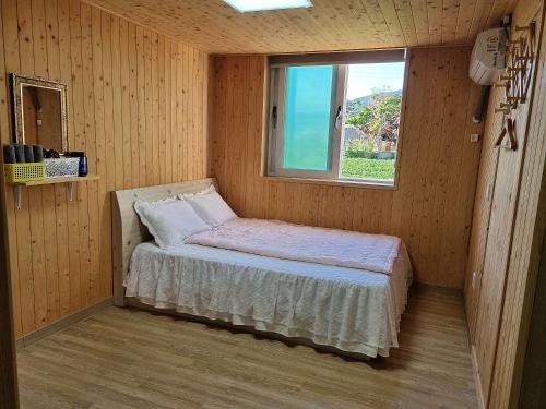 małe łóżko w pokoju z oknem w obiekcie Odaesan Moonlight w mieście Pjongczang