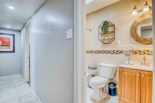 a bathroom with a toilet and a sink and a mirror at My Cozy Duplex A in the Heart of West Side in El Paso