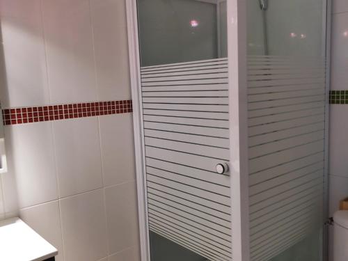 La salle de bains blanche est pourvue d'une porte de douche en verre. dans l'établissement Studio cosy avec balcon, au pied des pistes - 2 pers., kitchenette équipée, animations hiver/été - FR-1-689-109, à Villard-de-Lans