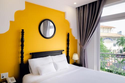 a bedroom with a bed with a yellow wall and a window at The Fancy House in Quy Nhon