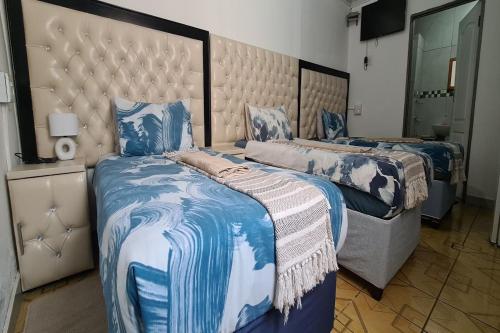 a bedroom with two beds with blue and white sheets at Maluti Backpackers in Phuthaditjhaba
