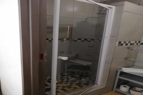 a bathroom with a shower with a glass door at Maluti Backpackers in Phuthaditjhaba
