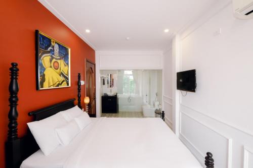 a bedroom with a white bed and an orange wall at The Fancy House in Quy Nhon