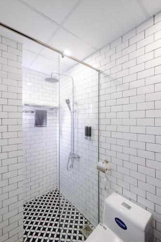 a white tiled bathroom with a shower and a toilet at The Fancy House in Quy Nhon