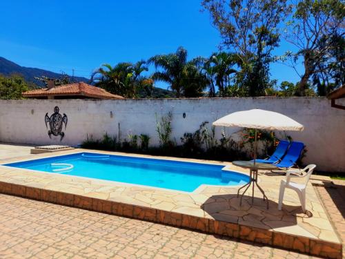 - Piscina con sombrilla, mesa y silla en Caraguá Sol e Mar 1, en Caraguatatuba