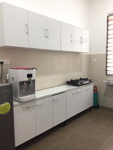 uma cozinha com armários brancos e um fogão em Rooma Singgah Homestay @ Cherating em Kuantan
