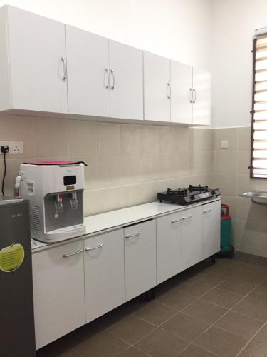 a kitchen with white cabinets and a stove in it at Rooma Singgah Homestay @ Cherating in Kuantan