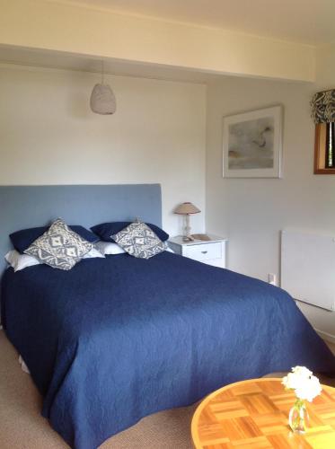 a bedroom with a blue bed and a table at Lakehouse Studio in Kerikeri