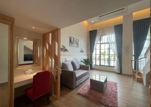 a living room with a couch and a red chair at Grand Lord Hotel & Residence - Khao chi chan Pattaya in Na Jomtien