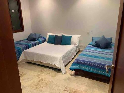 a bedroom with two beds with blue pillows at 212 Cartagena Walled City Magical Apt in Cartagena de Indias