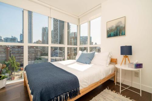 a bedroom with a bed and large windows at Sunset Beach Walk 2BD+2BA+1PRK Yaletown in Vancouver
