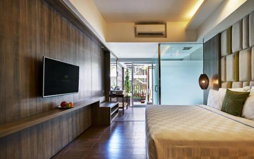 1 dormitorio con 1 cama y TV en la pared en The Crystal Luxury Bay Resort Nusa Dua, en Nusa Dua