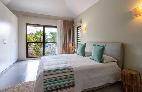 a bedroom with a large bed with a large window at VILLA CHAMAREL in Flic-en-Flac