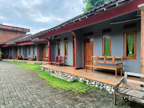 a building with benches on the side of it at Jogo Segoro Homestay Mitra RedDoorz near Pantai Sundak Gunungkidul in Ngandong