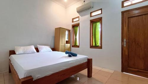 un dormitorio con una cama con un osito de peluche sentado en ella en Jogo Segoro Homestay Mitra RedDoorz near Pantai Sundak Gunungkidul, en Ngandong