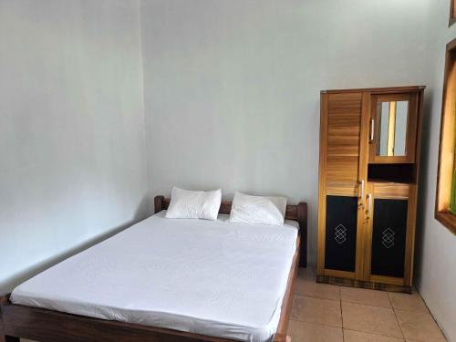 a bedroom with a white bed and a wooden door at Jogo Segoro Homestay Mitra RedDoorz near Pantai Sundak Gunungkidul in Ngandong