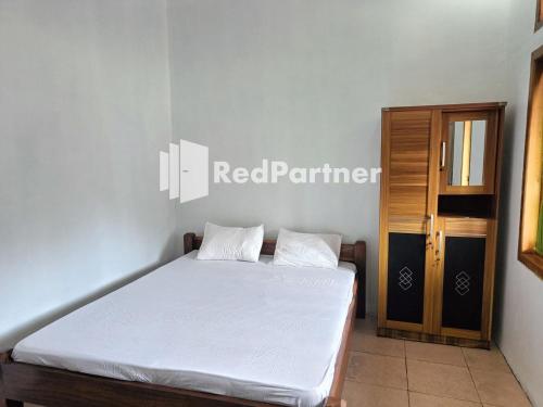 a bedroom with a white bed and a wooden door at Jogo Segoro Homestay Mitra RedDoorz near Pantai Sundak Gunungkidul in Ngandong