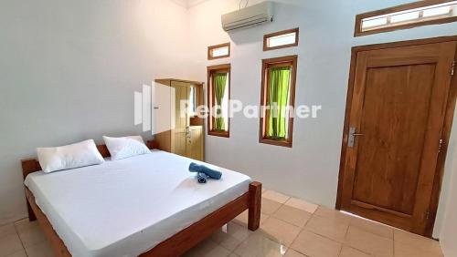 a bedroom with a bed and a wooden door at Jogo Segoro Homestay Mitra RedDoorz near Pantai Sundak Gunungkidul in Ngandong