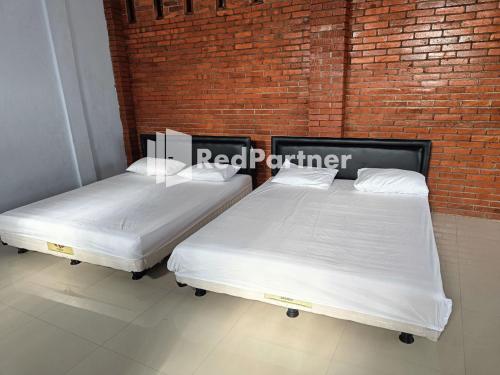 two beds in a room next to a brick wall at Jogo Segoro Homestay Mitra RedDoorz near Pantai Sundak Gunungkidul in Ngandong