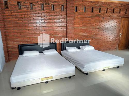 two beds in a room with a brick wall at Jogo Segoro Homestay Mitra RedDoorz near Pantai Sundak Gunungkidul in Ngandong