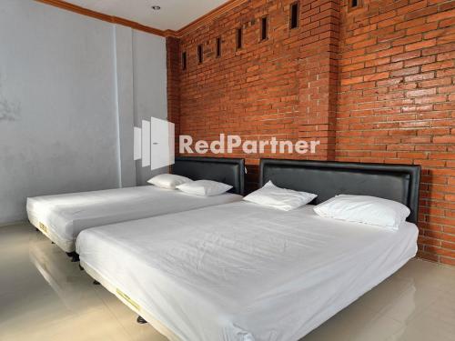 two beds in a room with a red brick wall at Jogo Segoro Homestay Mitra RedDoorz near Pantai Sundak Gunungkidul in Ngandong