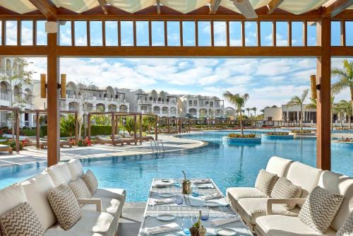 a pool at a resort with white chairs and a table at Steigenberger Resort Alaya Marsa Alam - Red Sea - Adults Friendly 16 Years Plus in Coraya Bay