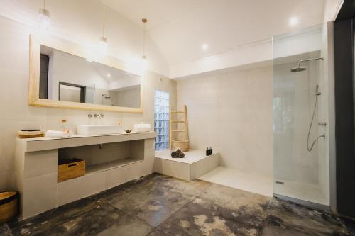 ein Bad mit einer Dusche, einem Waschbecken und einem Spiegel in der Unterkunft Indiana Kenanga Boutique Hotel & Spa in Nusa Lembongan