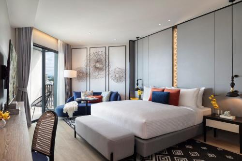 a bedroom with a large bed and a living room at Somerset Pattaya - SHA Plus in Pattaya Central