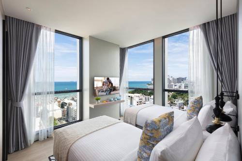a hotel room with two beds and a large window at Somerset Pattaya in Pattaya Central