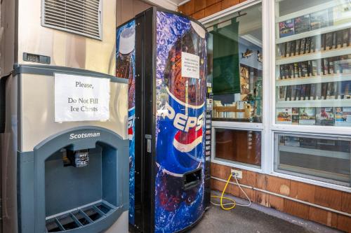 Una máquina de refrescos en una tienda con un cartel. en Sailor Jack Oceanfront Motel en Lincoln City