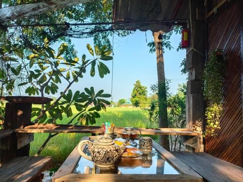 a table with a tea pot and a view of a field at Sukhothai City Resort in Sukhothai