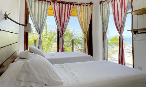 two beds in a bedroom with a large window at Mi Playa Beach Front Isabela in Puerto Villamil