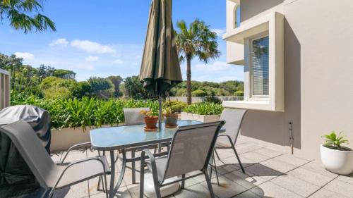 a patio with a table and chairs and an umbrella at 5 - 13 - 15 Beach Road, Hawks Nest in Hawks Nest