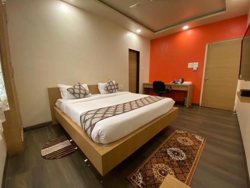 a bedroom with a large bed with an orange wall at WOWstops VENUS in Pune