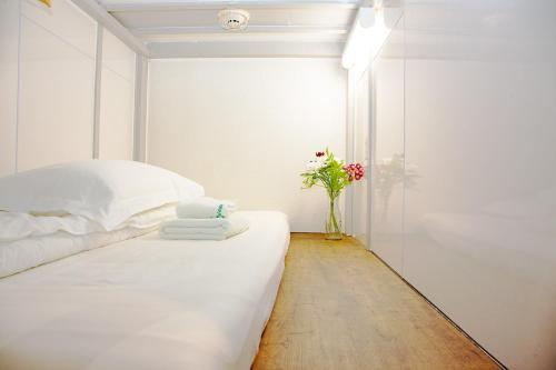 een witte slaapkamer met een bed en een vaas met bloemen bij Guest House Siesta in Tokyo