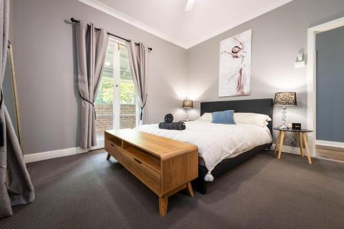 1 dormitorio con cama, mesa y ventana en Tatbern Park Cottage Wallalong, en Wallalong