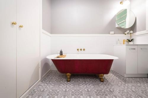 a white bathroom with a red tub in it at Tatbern Park Cottage Wallalong in Wallalong
