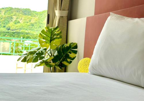 a bed with a white pillow next to a window at 小逗民宿 in Taitung City