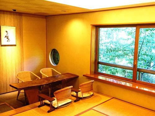 a room with a table and chairs and a window at Hanafubuki in Ito