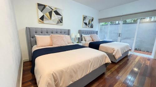 a bedroom with two beds and a large window at Spacious Villa Holiday Staycation in Canterbury East of Melbourne in Balwyn
