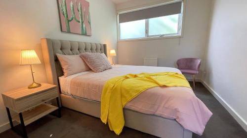 a bedroom with a bed with a yellow blanket on it at Spacious Villa Holiday Staycation in Canterbury East of Melbourne in Balwyn