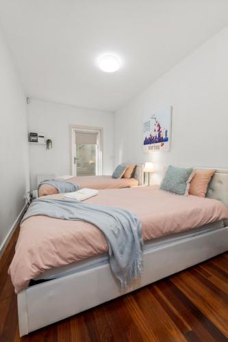 a white bedroom with two beds with pink sheets at Spacious Villa Holiday Staycation in Canterbury East of Melbourne in Balwyn