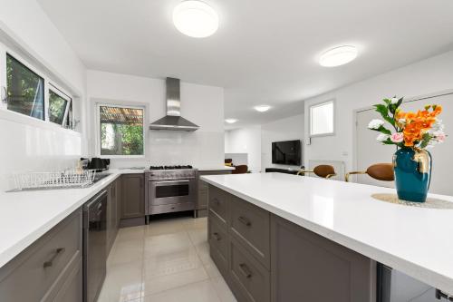 a kitchen with white counters and a vase of flowers at Spacious Villa Holiday Staycation in Canterbury East of Melbourne in Balwyn