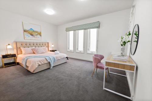 a white bedroom with a bed and a desk and a desk at Spacious Villa Holiday Staycation in Canterbury East of Melbourne in Balwyn