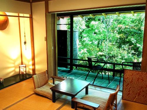 a living room with a table and chairs and a balcony at Hanafubuki in Ito