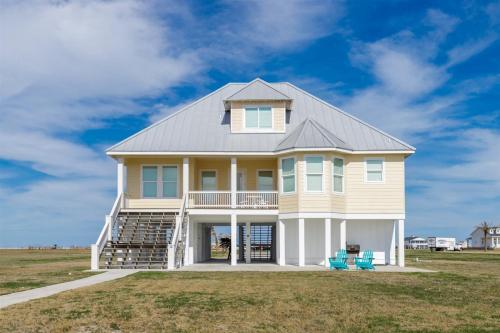 una casa grande con 2 sillas azules en un campo en Sea Forever - Rockport, en Rockport