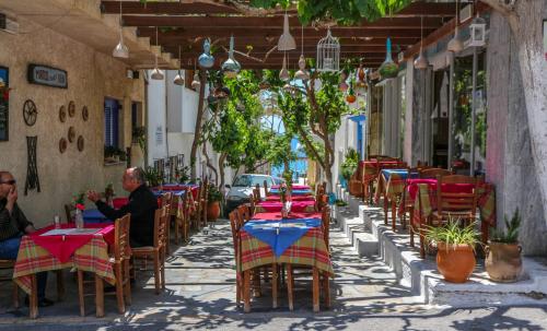 a man sitting at a table in an outdoor restaurant at Mirtos Hotel in Myrtos
