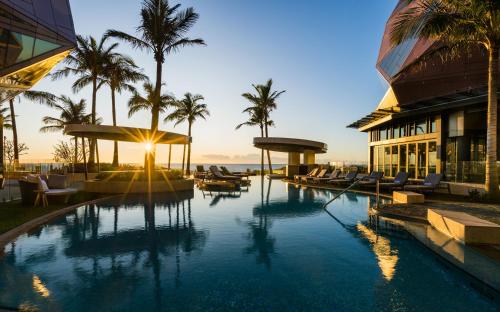 a resort pool with palm trees and a building at The Langham, Gold Coast and Jewel Residences in Gold Coast